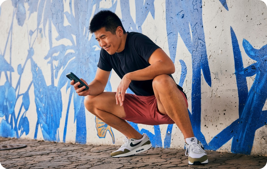 A person standing on a sidewalk with a cell phone.