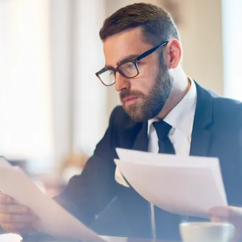 A bearded man in suit reading files