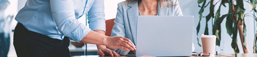 Two office people talking in front of a laptop