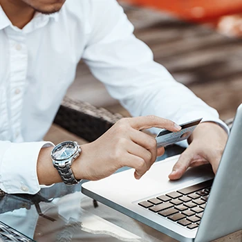 A business man using a laptop while holding a credit card