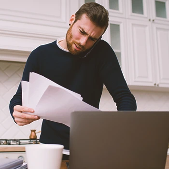 A business owner looking at paperwork while using the laptop